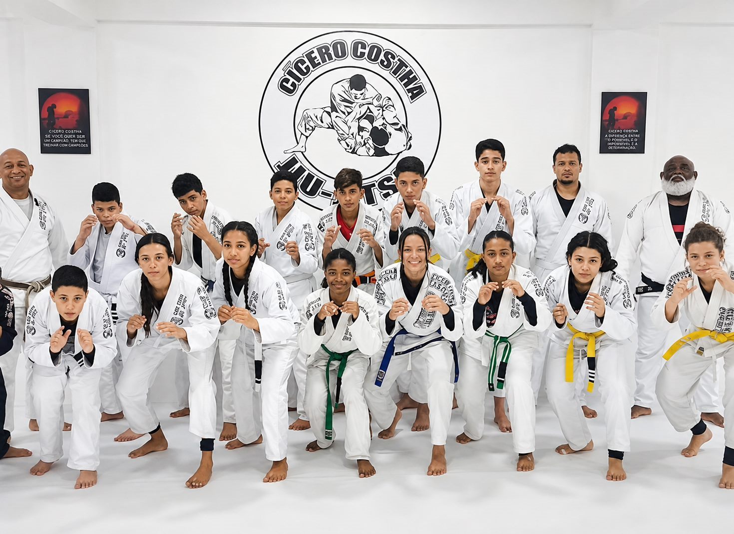 Turma de jiu-jitsu infantil e juvenil da Cícero Costha em posição de guarda, diante do emblema da equipe